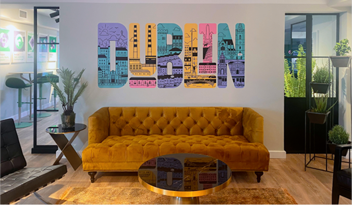 La oficina de Sprout Social en Dublín, que muestra un área de descanso con un sofá, dos pequeñas mesas de café y un mural.