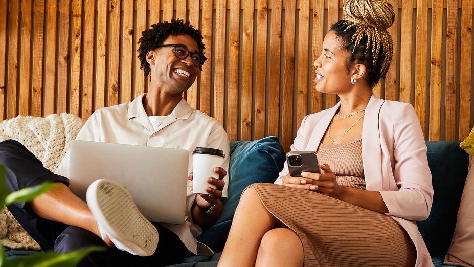 Two people on a couch smiling and looking at each other, representing the positive human connections fostered through social media.